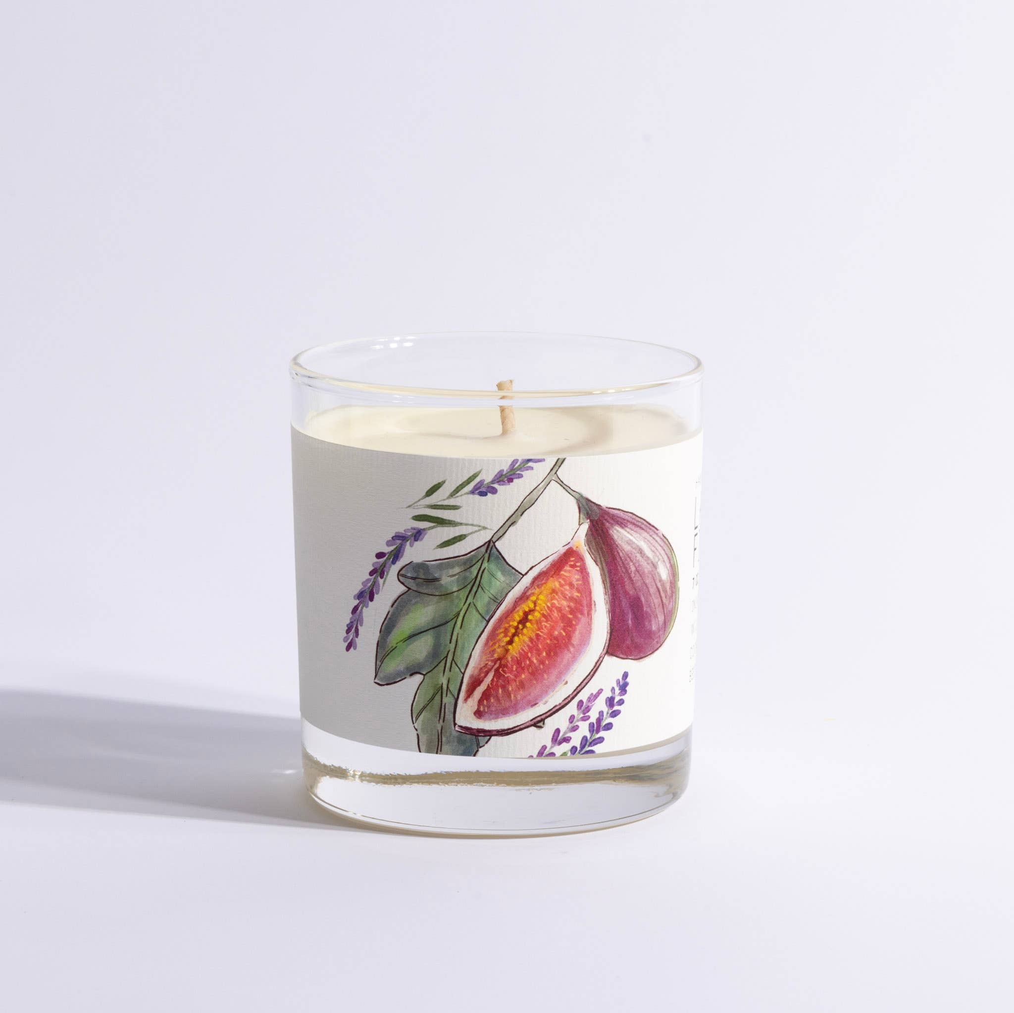 Candle in a glass jar with fig and lavender design on a light gray background