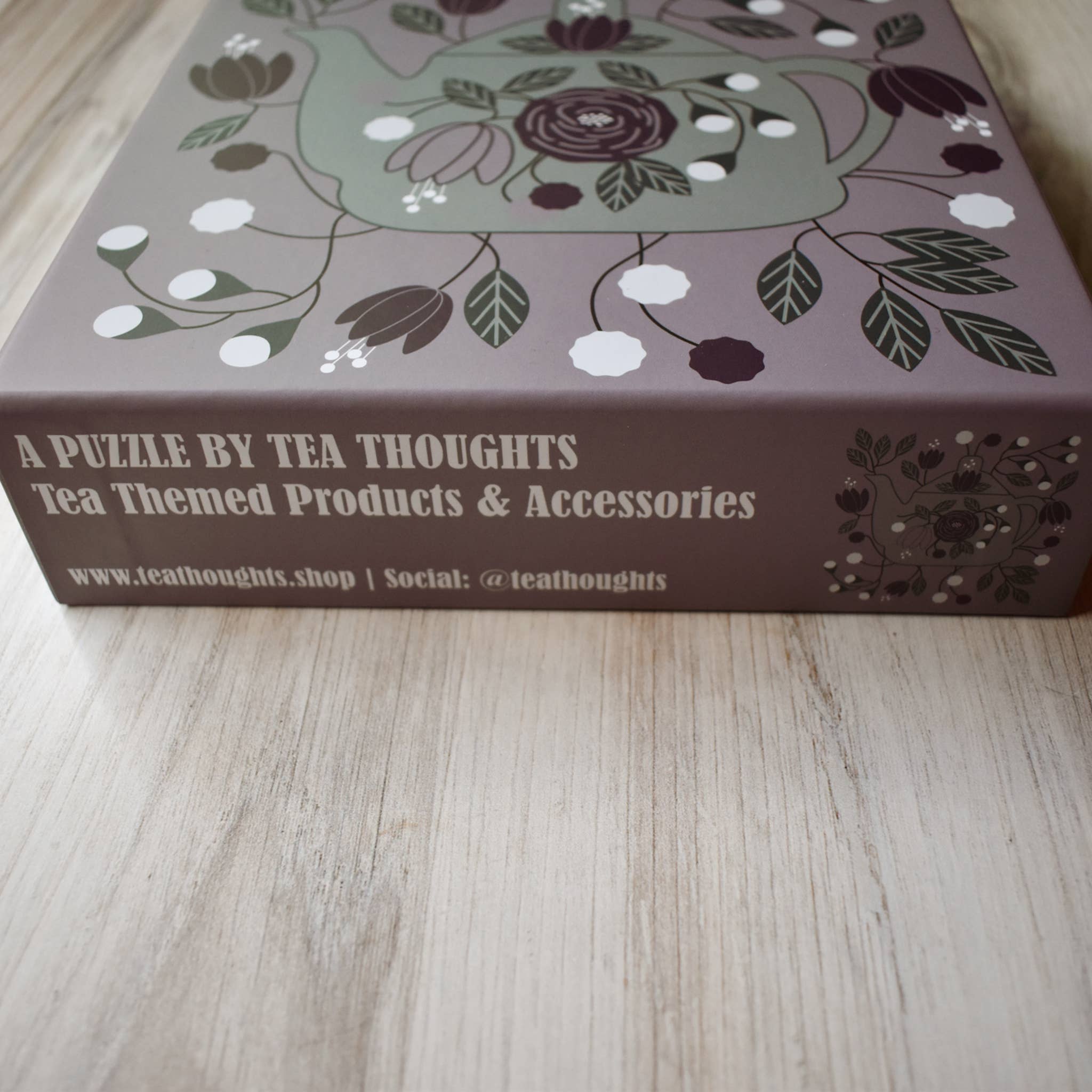 Tea-themed puzzle packaging with floral design on a wooden surface