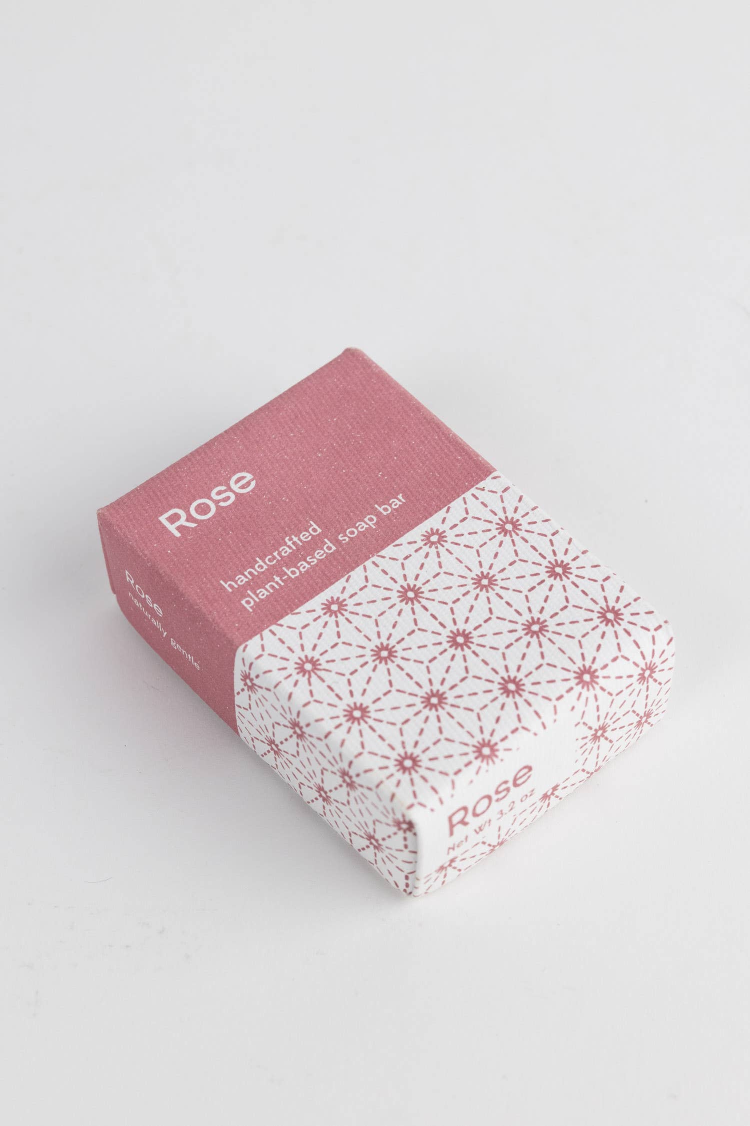 Bar of soap with a pink packaging box on a light gray background