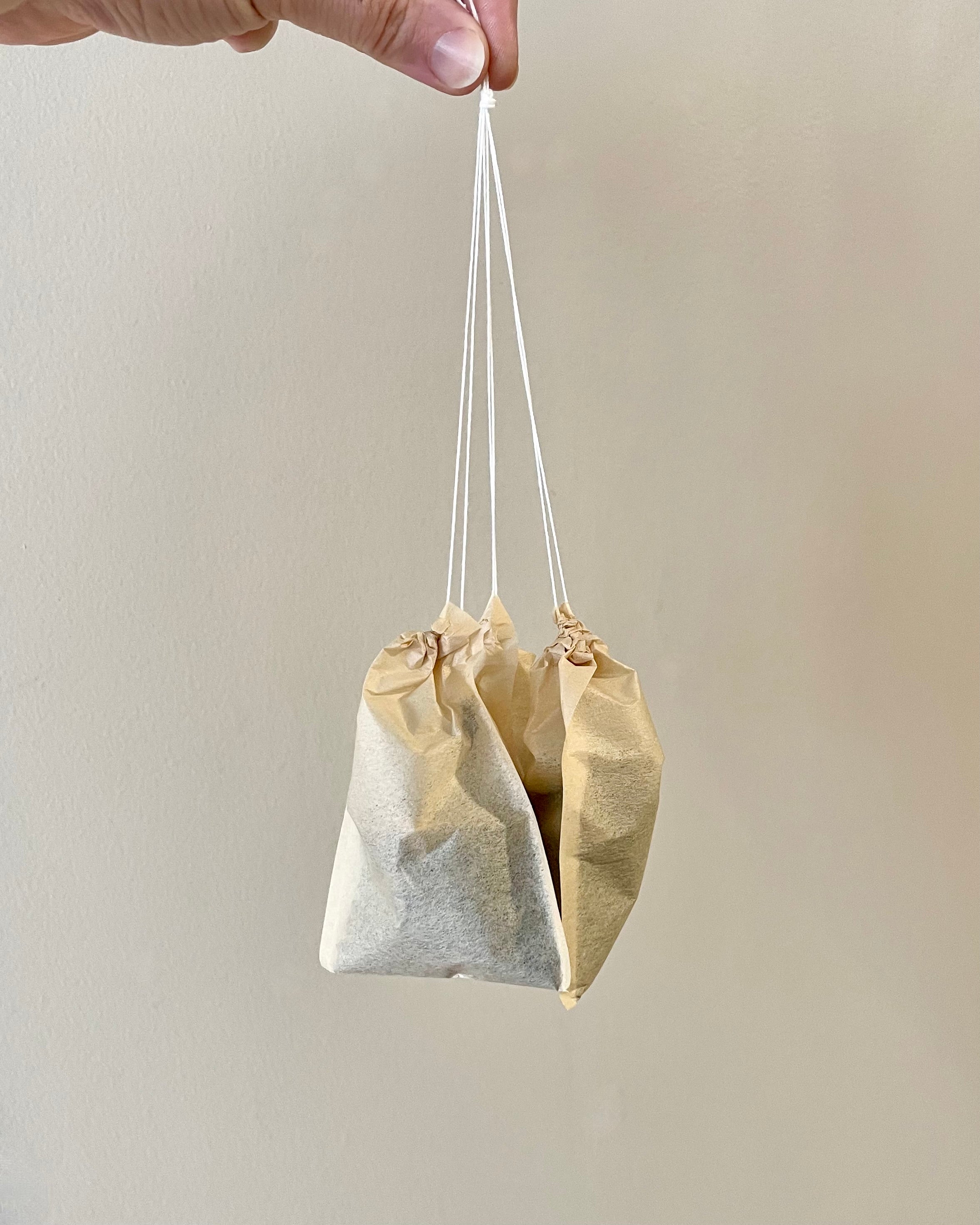 Three tea bags tied together against a plain background