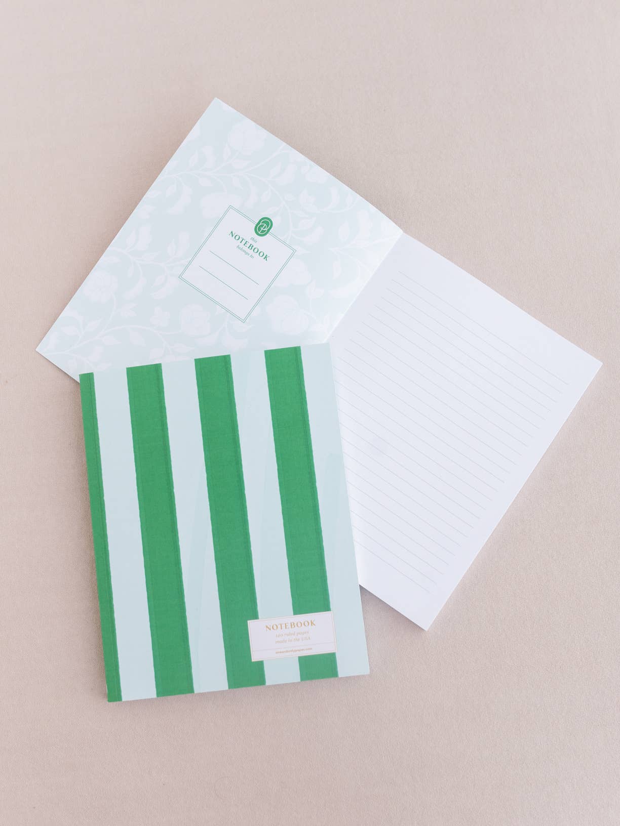 Green and white striped notebook with a matching cover on a beige background