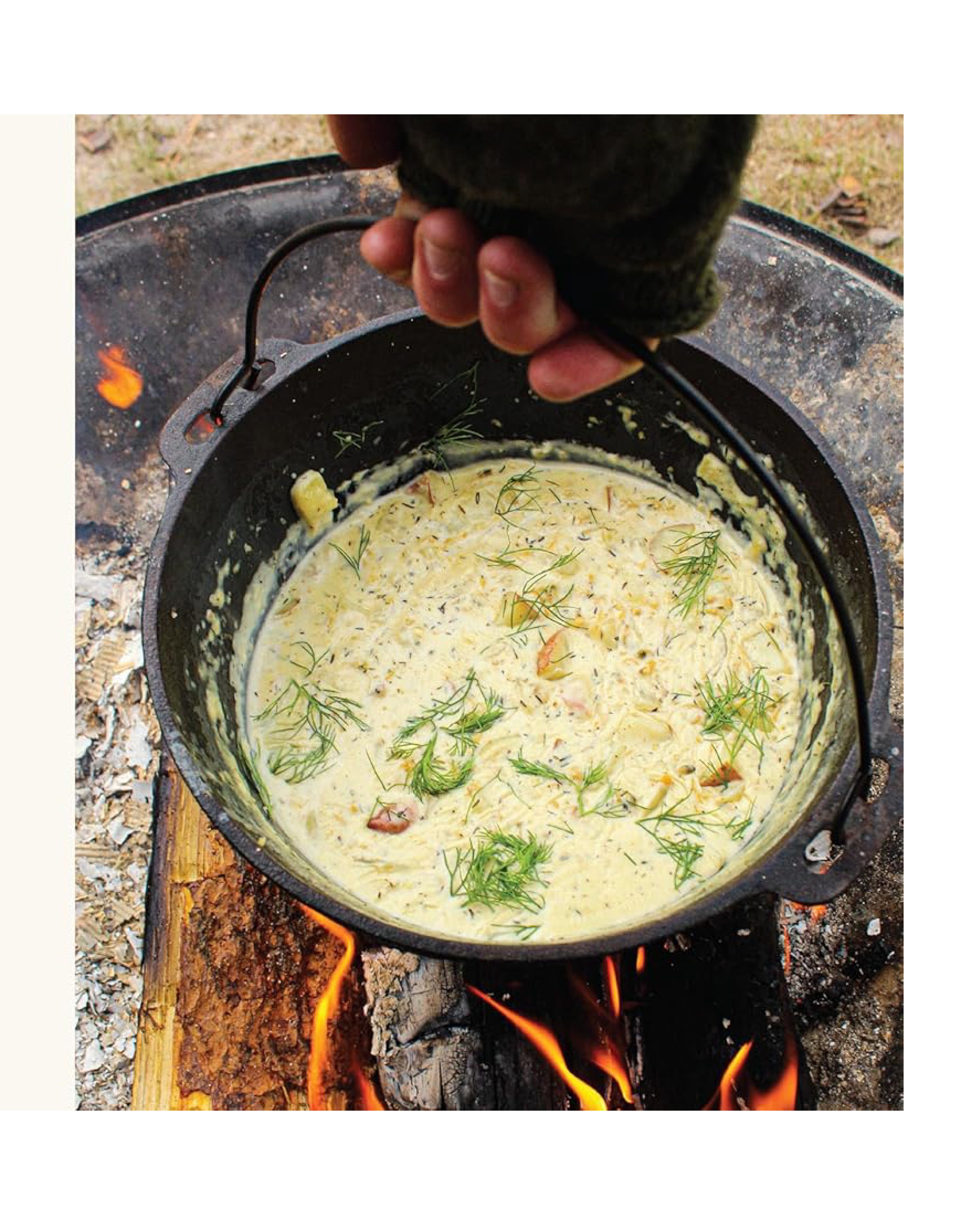 Dutch oven with creamy dish over a campfire