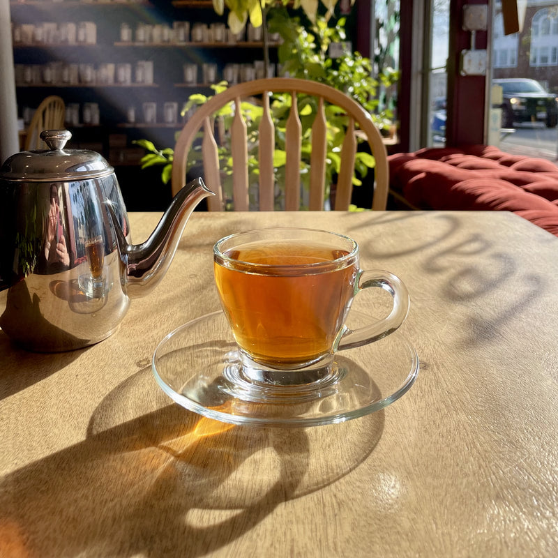 Tea cup with saucer and silver teapot on a wooden table in a cafe setting