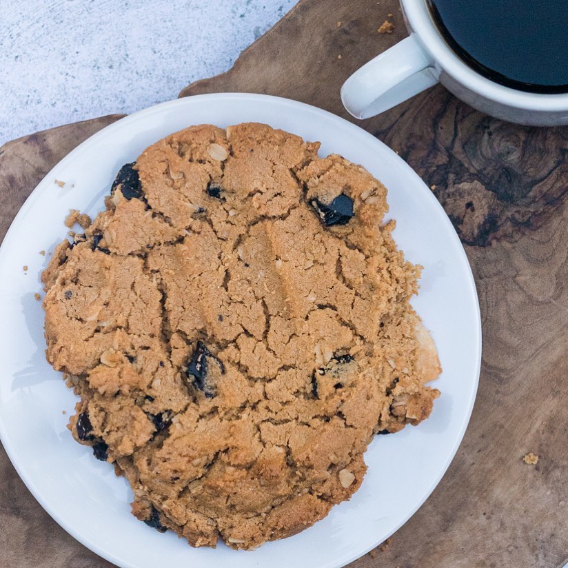 Cookie on a white plate with a cup of coffee on a wooden surface