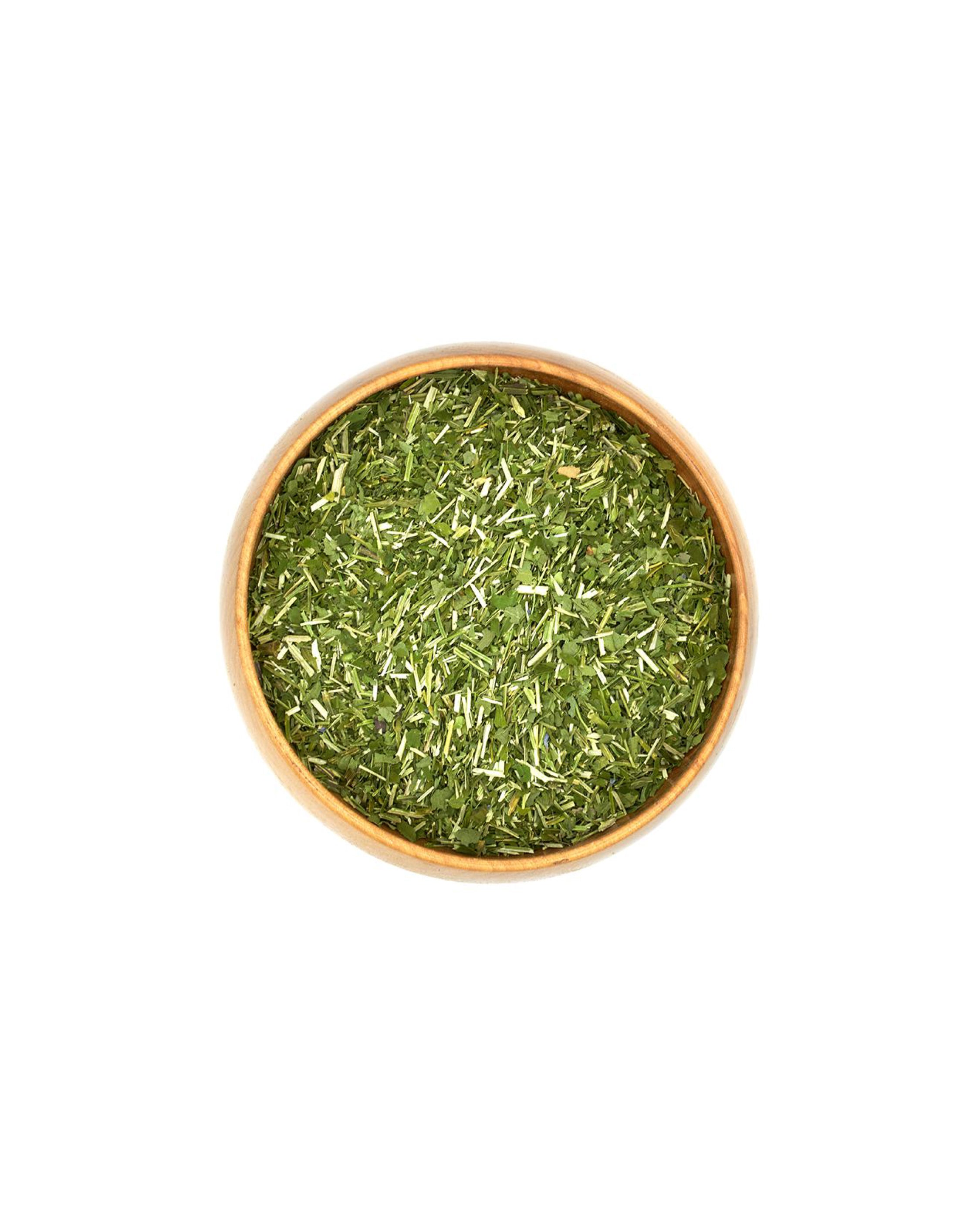 Bowl of green dried herbs on a white background