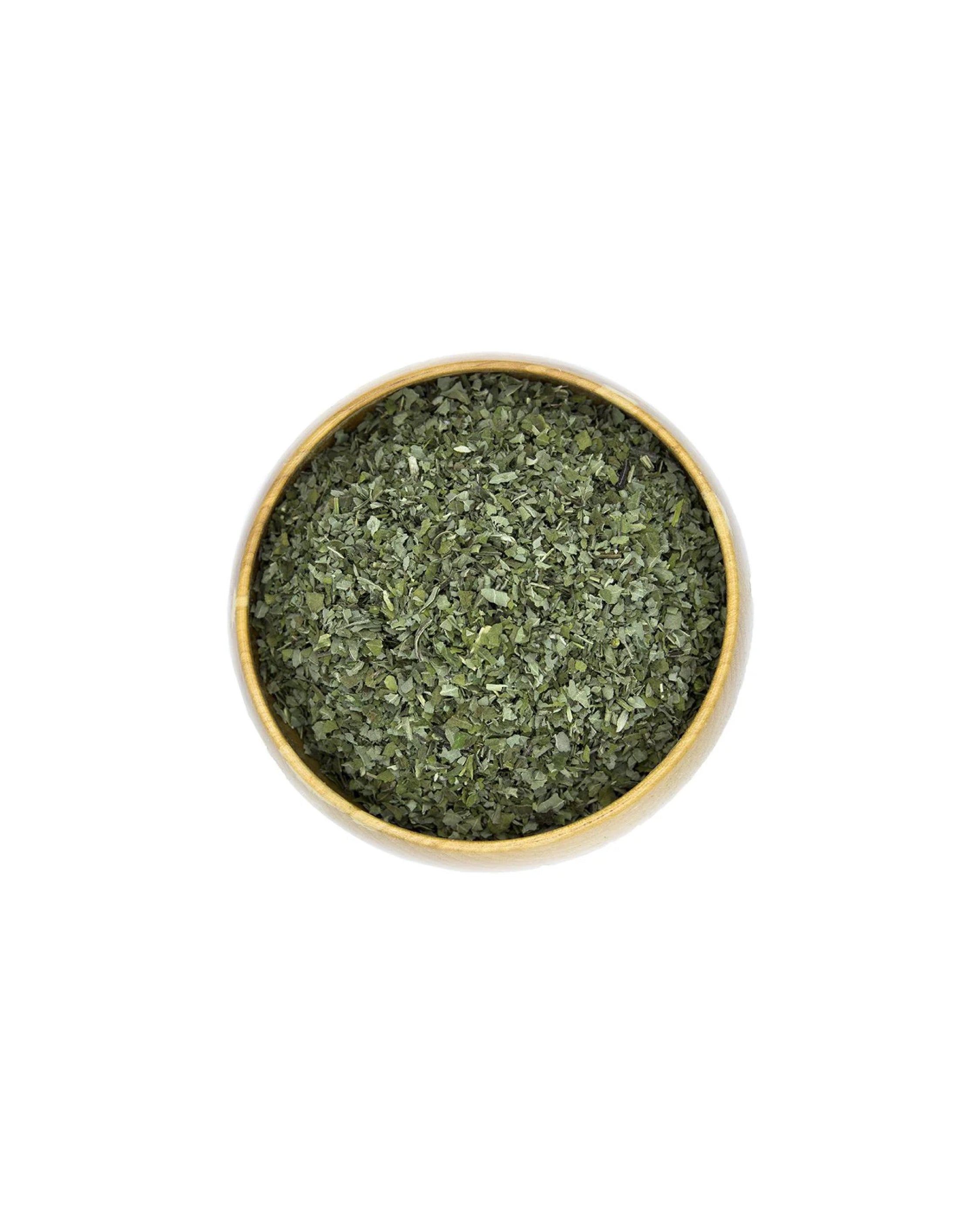 Bowl filled with dried herbs on a white background