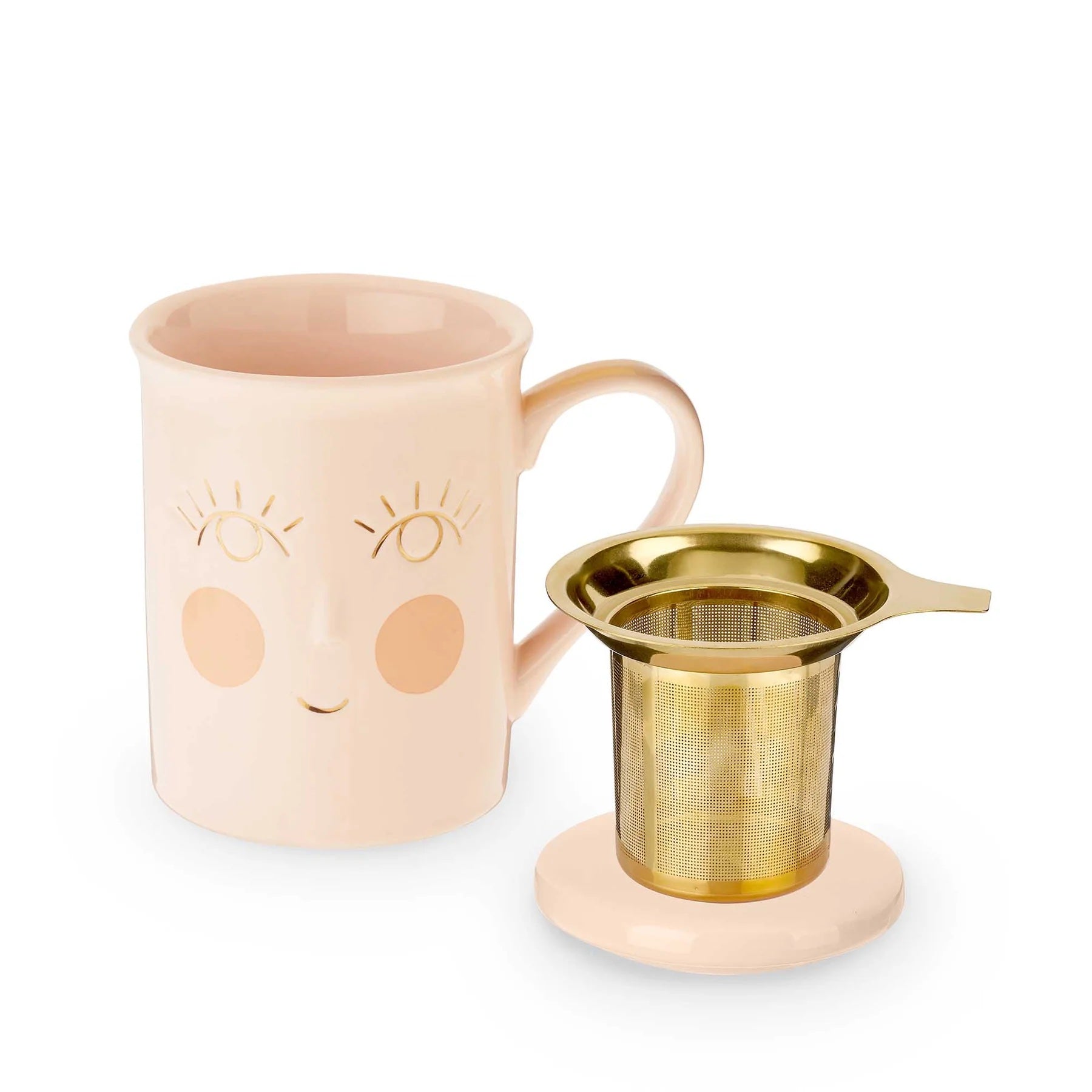 Pink mug with face design and gold tea infuser on a white background