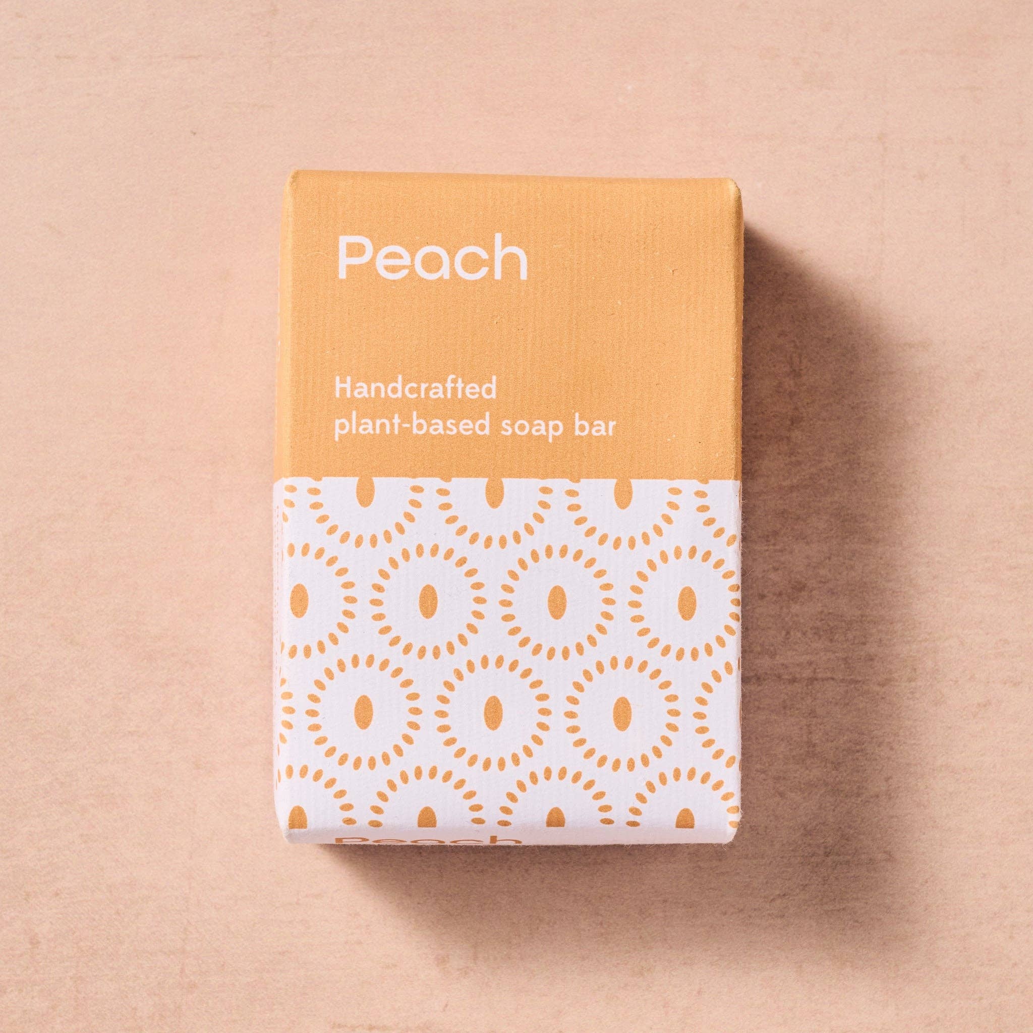 Handcrafted plant-based soap bar packaging with peach color on a beige background