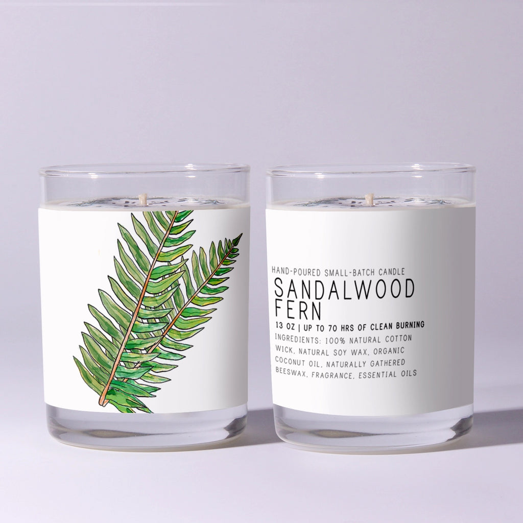 Two candles with labels, one featuring a fern illustration and the other text about sandalwood fern.