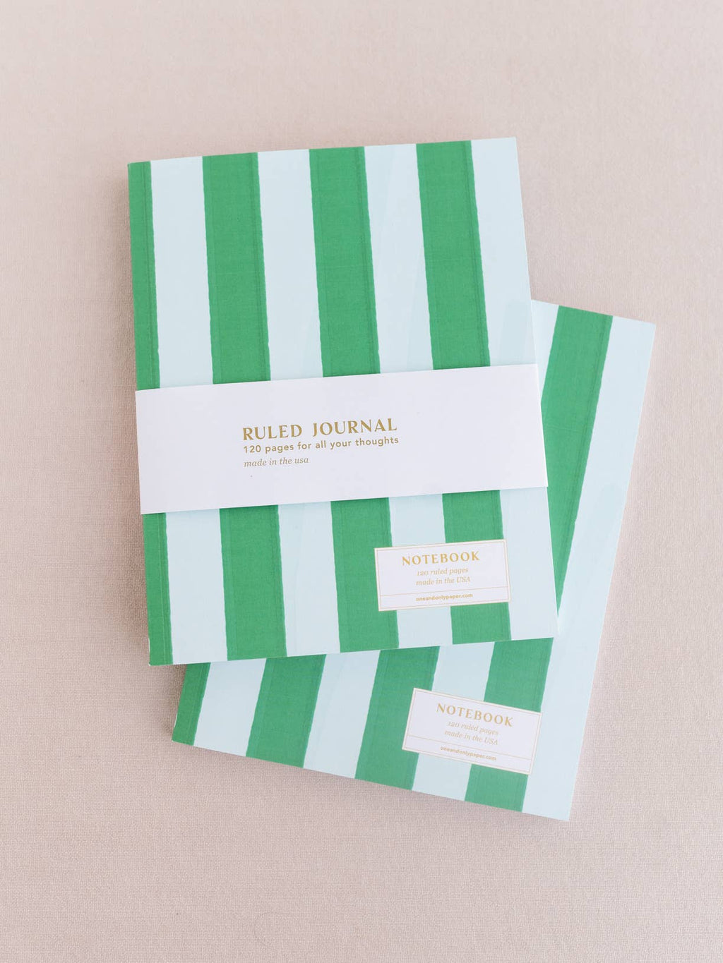 Two green and white striped notebooks on a beige background