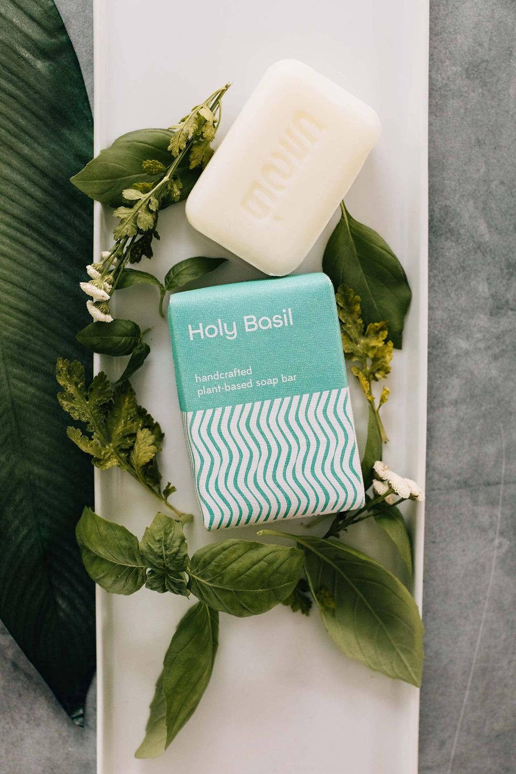 'Holy Basil' bar of soap on a white tray with green leaves.