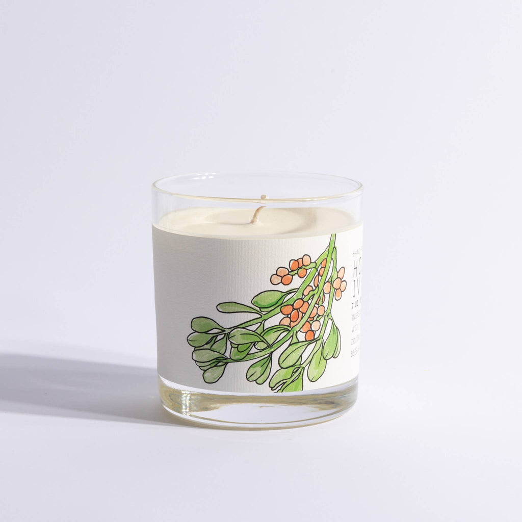 Candle in a glass jar with a mistletoe design on a light gray background