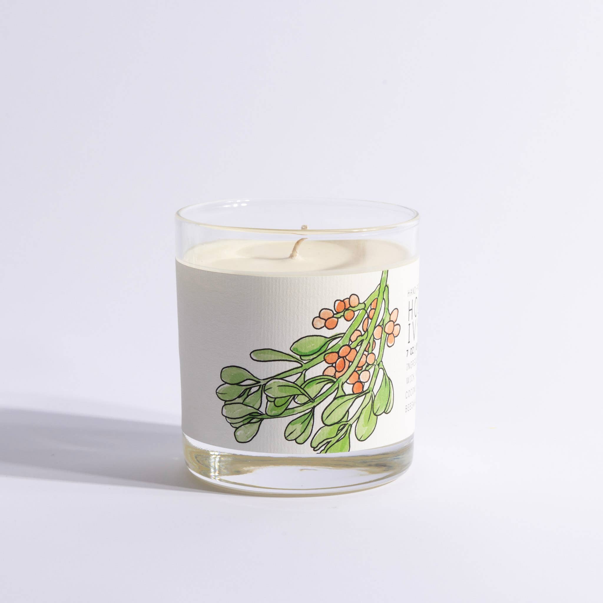 Candle in a glass jar with a mistletoe design on a light gray background