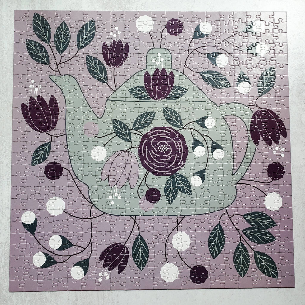 Jigsaw puzzle with a floral teapot design on a purple background