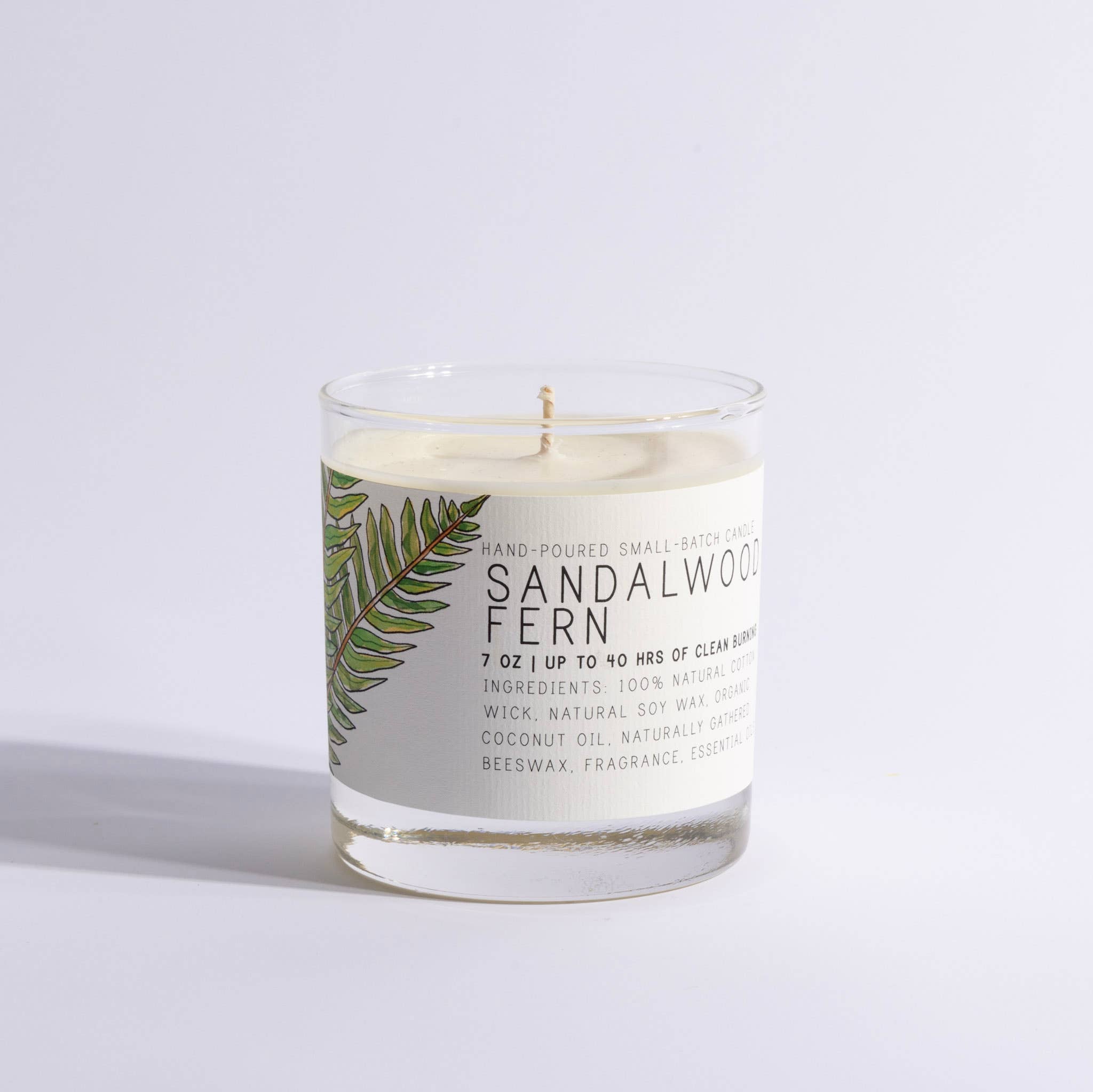 Sandalwood Fern candle in a clear glass container on a light gray background
