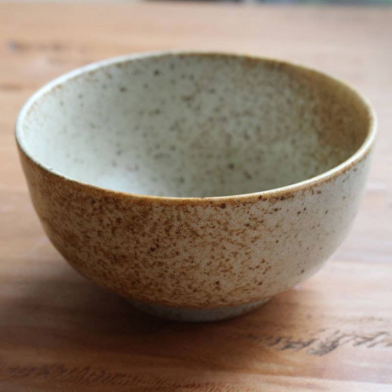 Speckled ceramic bowl on a wooden surface