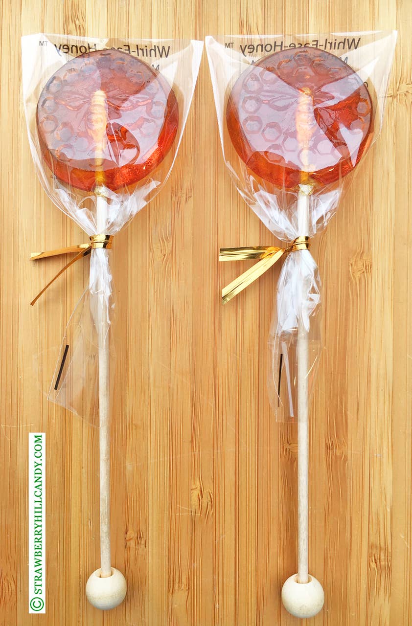 Two honeycomb swirl sticks in clear packaging on a wooden background.
