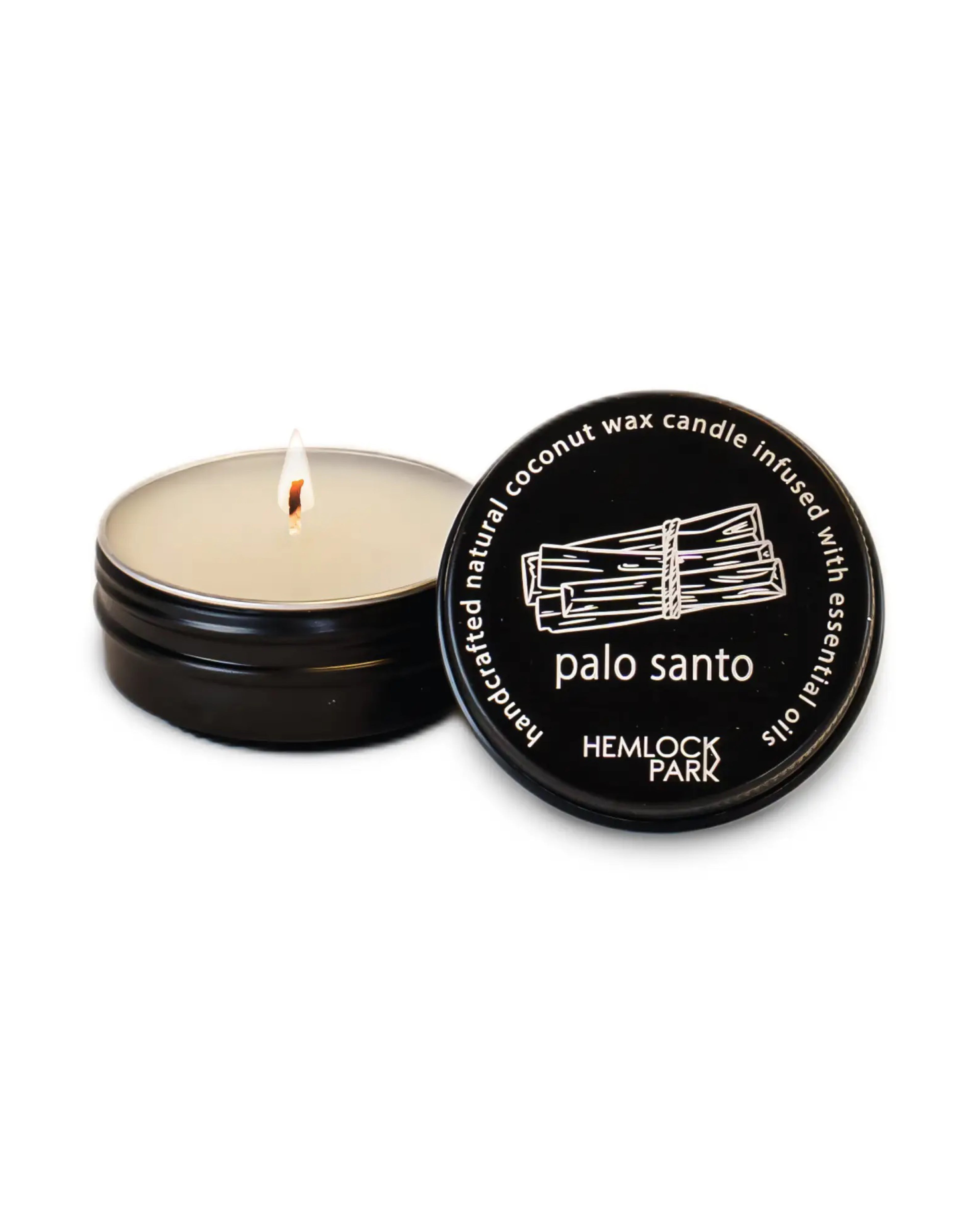Hemlock Park candle with lit wick and black lid on a white background
