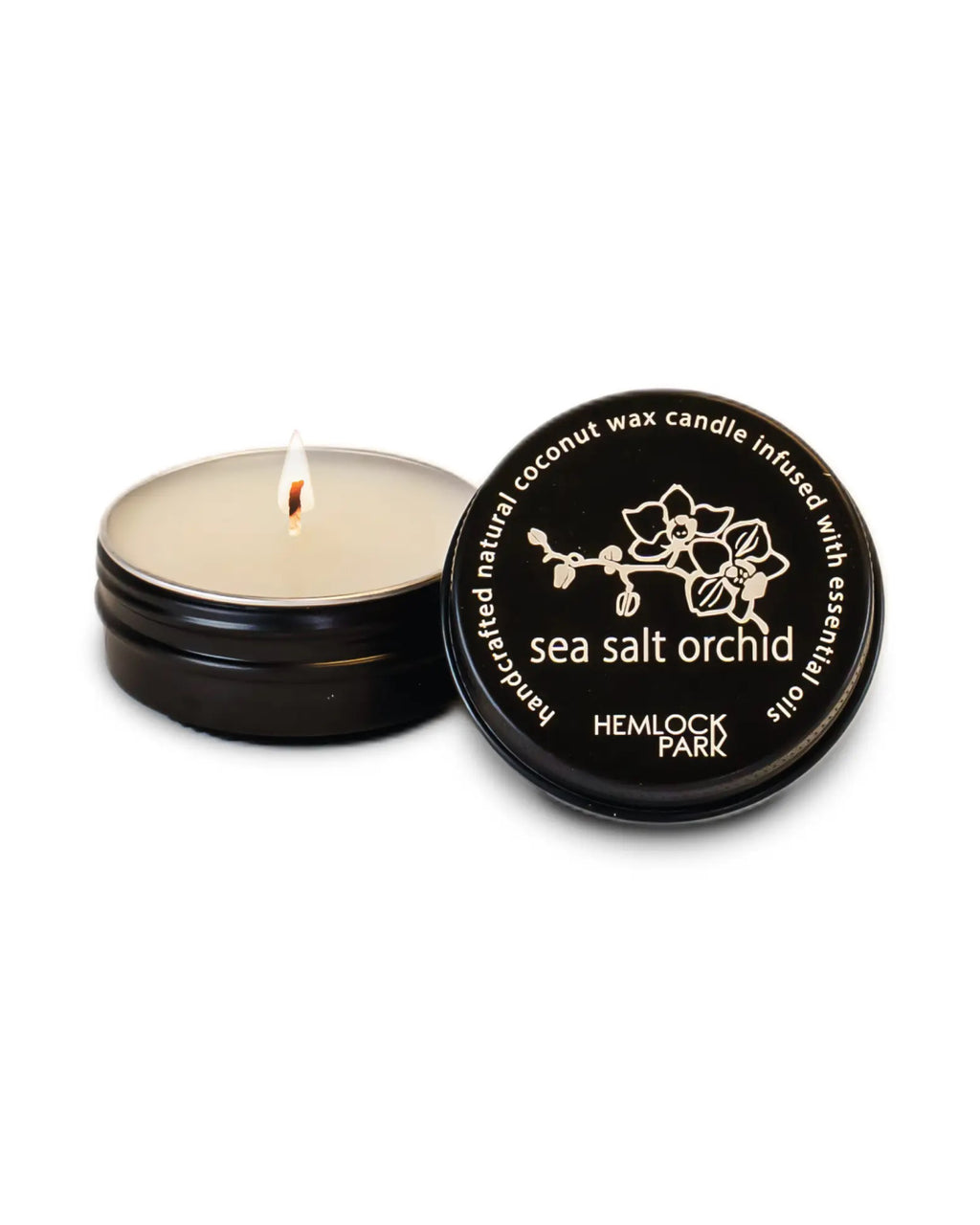 Hemlock Park candle with lit wick and black lid on a white background
