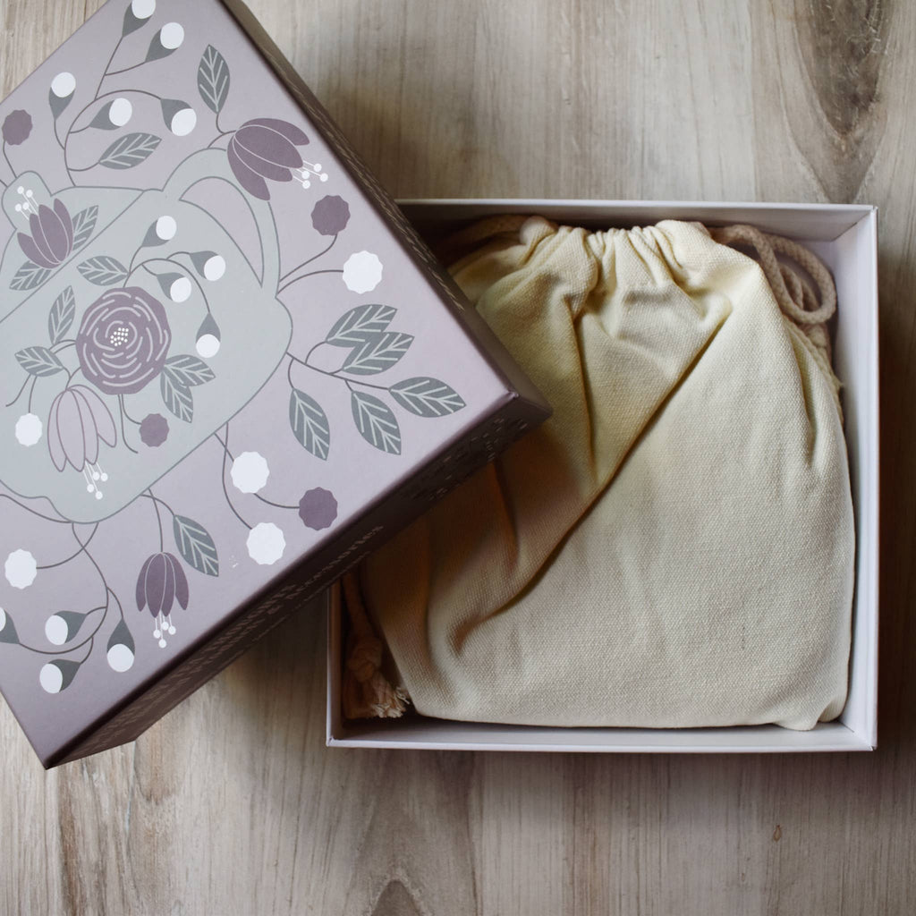 Drawstring bag with floral-patterned box on a wooden surface