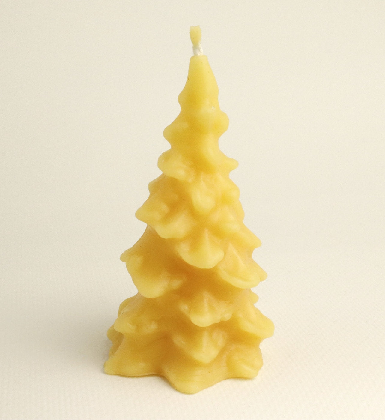 Beeswax candle shaped like a Christmas tree on a beige background