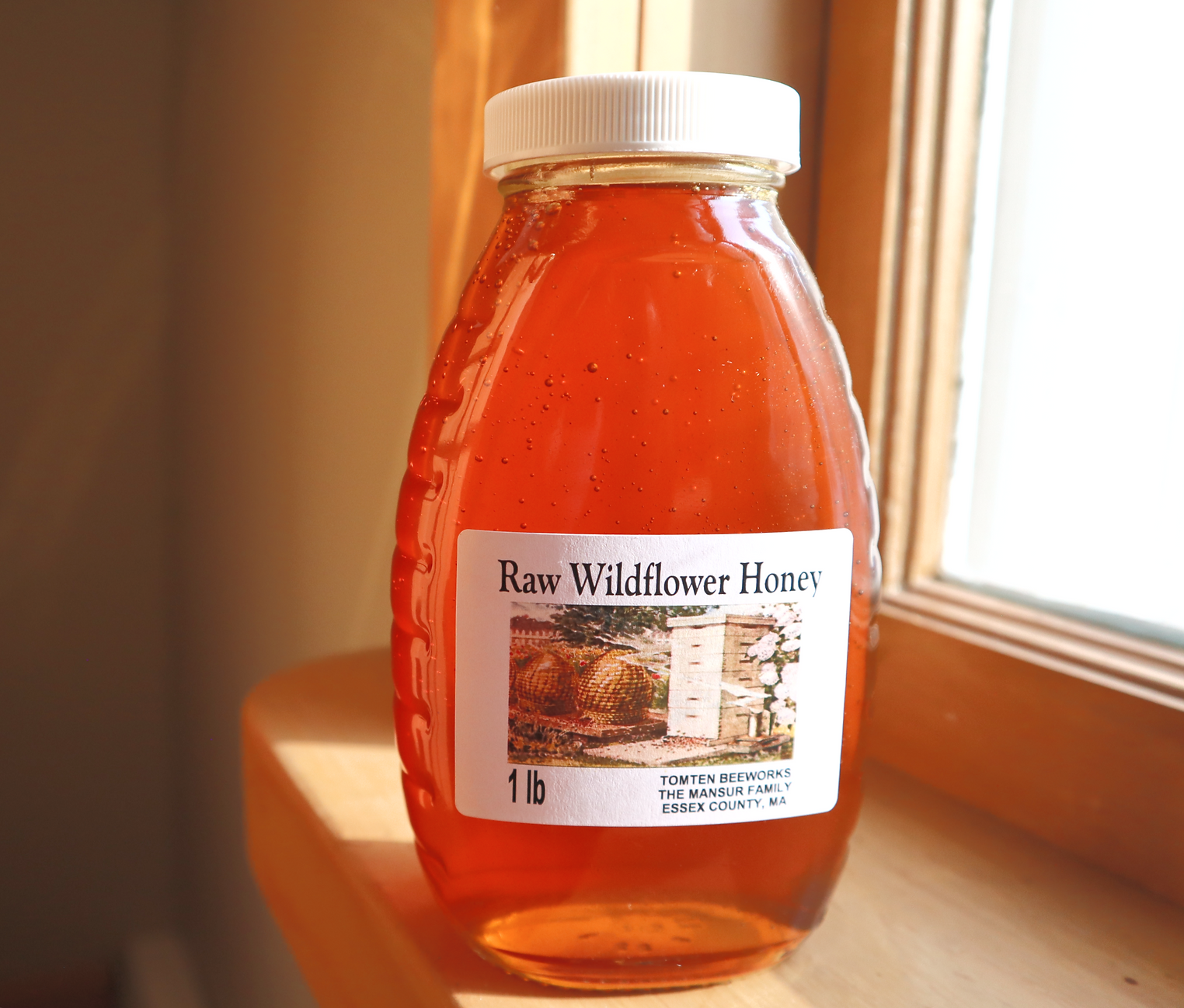 Bottle of raw wildflower honey on a windowsill