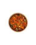 Bowl of dried marigold flowers on a white background
