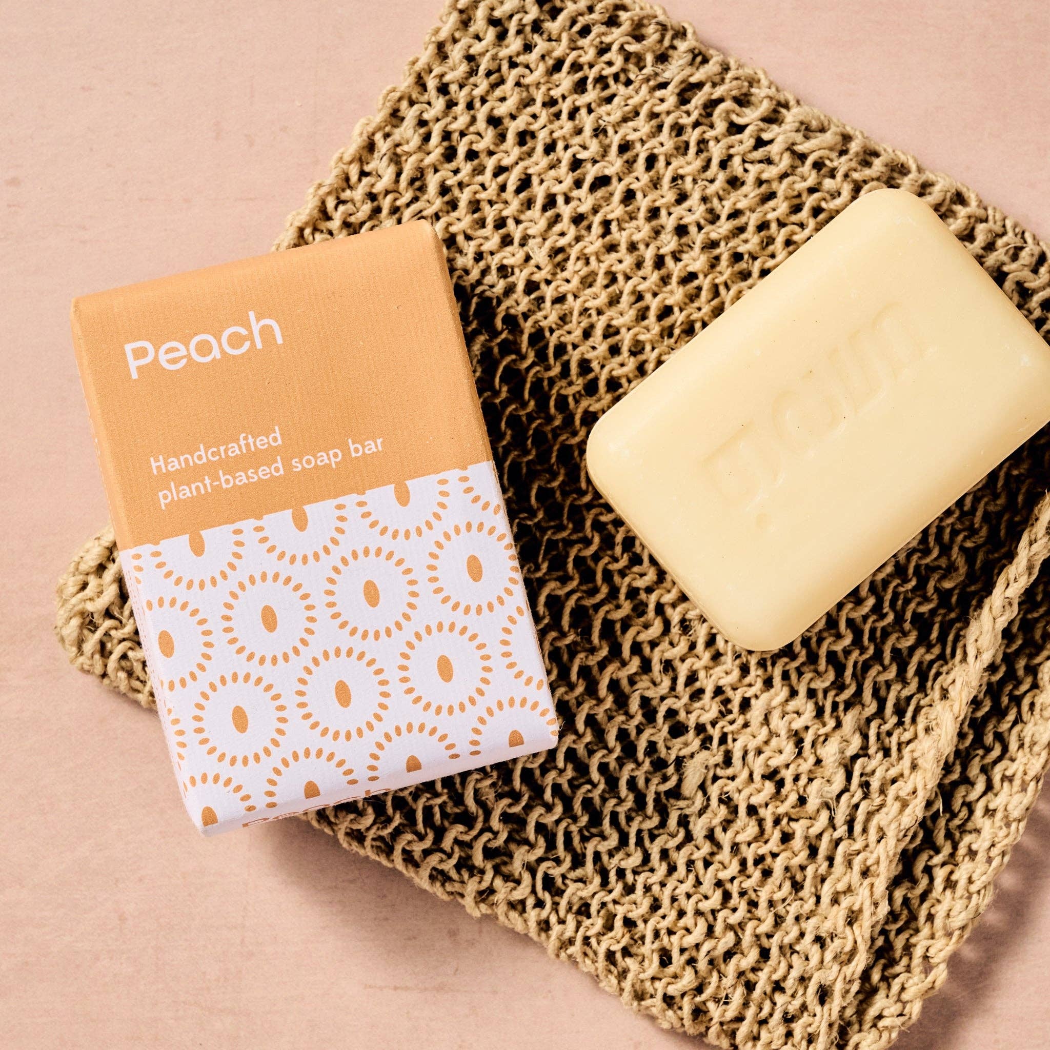 Handcrafted plant-based soap bar with packaging on a textured surface