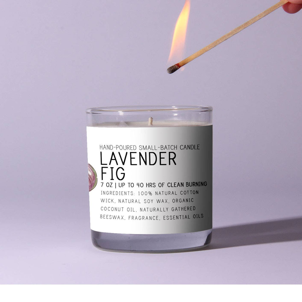 Candle labeled 'Lavender Fig' being lit with a match against a light purple background