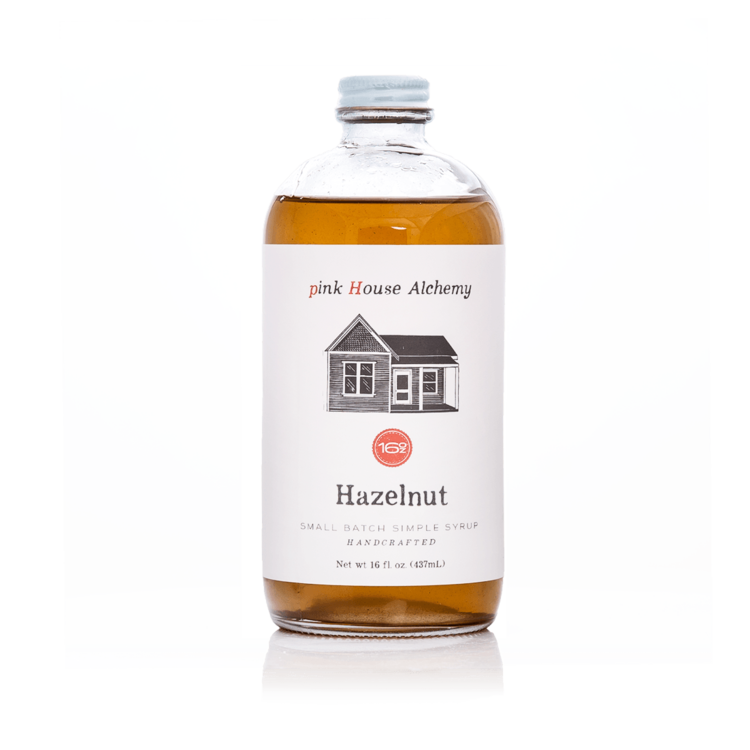 Bottle of hazelnut syrup from pink House Alchemy on a white background