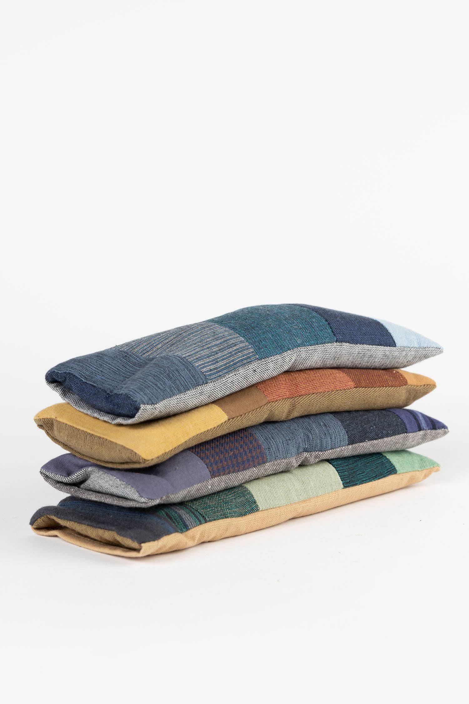 Stack of colorful fabric eye pillows on a white background
