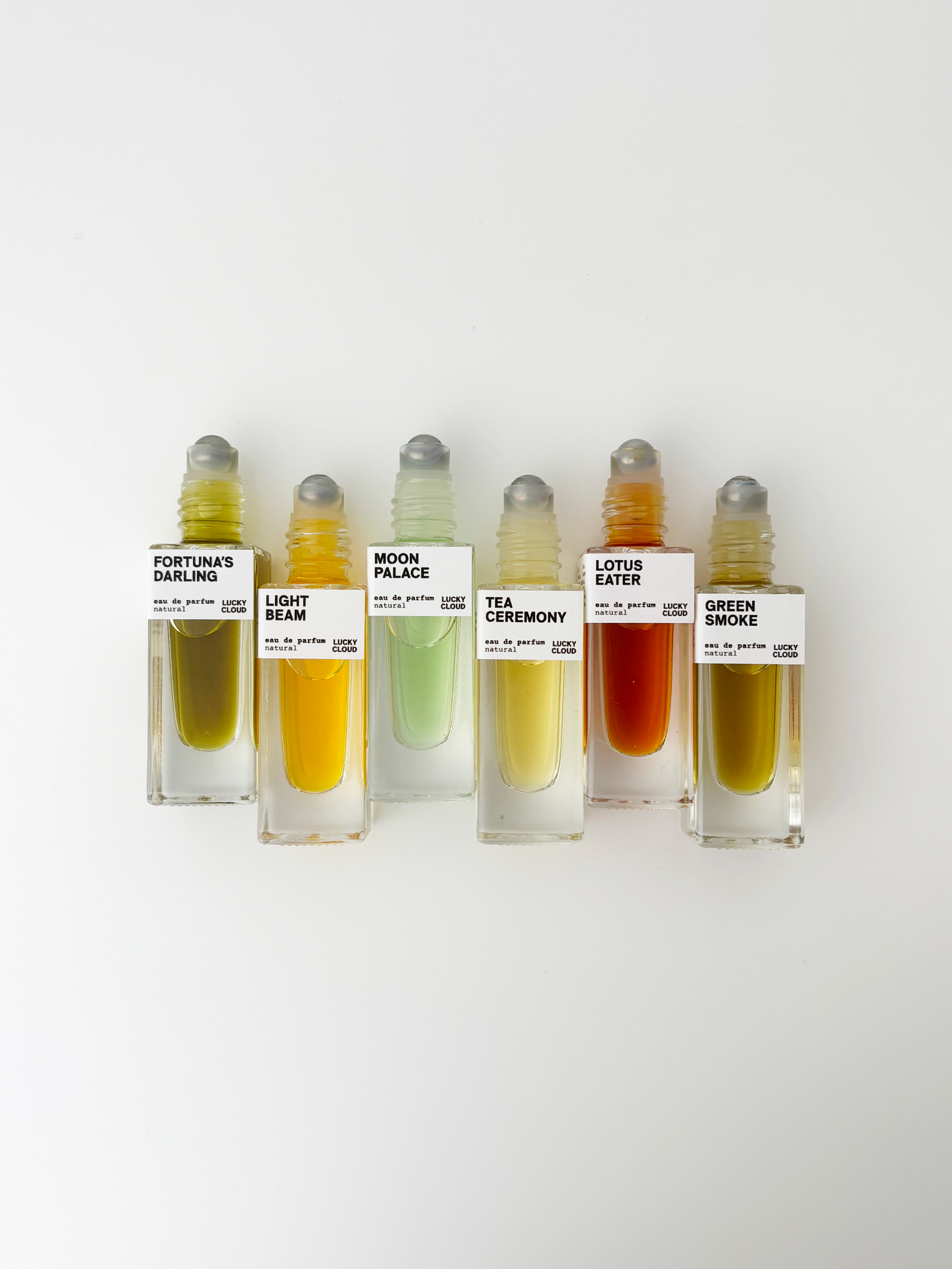 Set of six small perfume bottles with labels on a white background