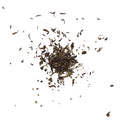 Dry tea leaves scattered on a white background