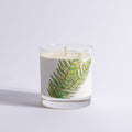 Candle in a glass jar with a fern leaf design on a light gray background