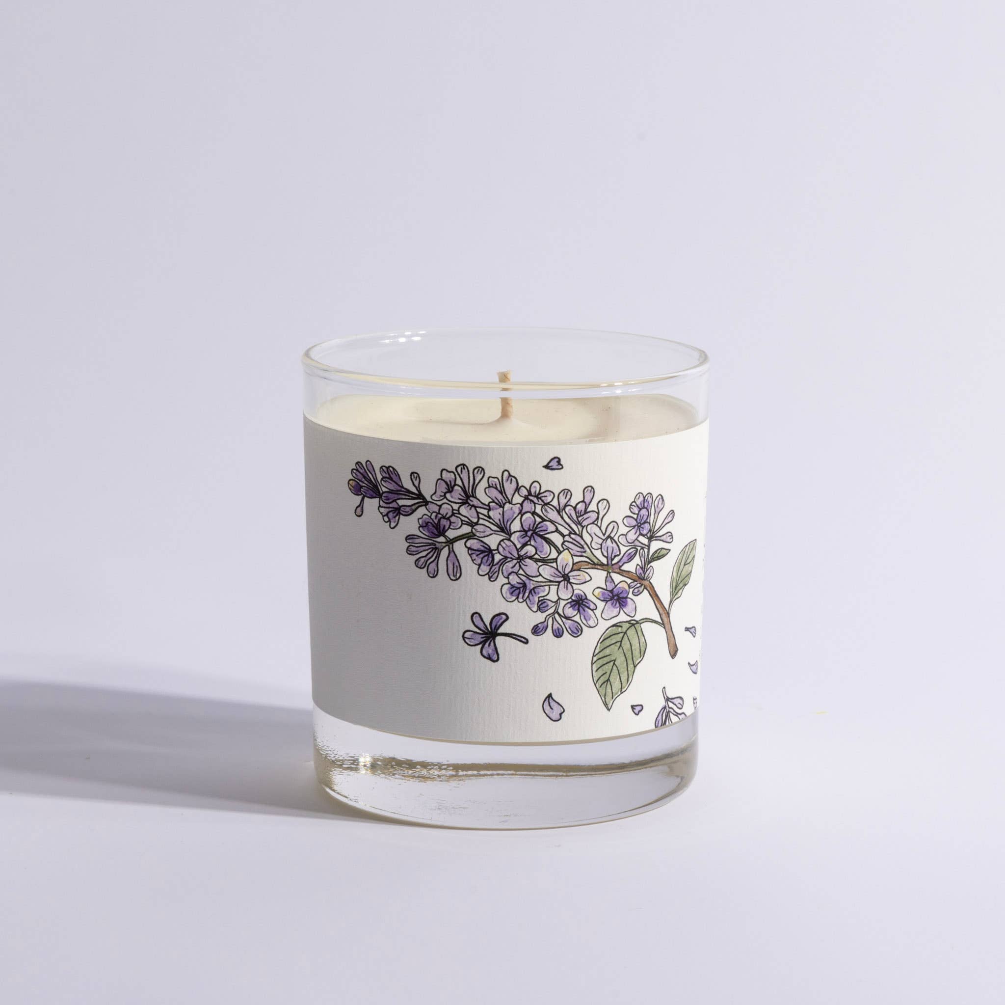 Candle in a glass jar with floral design on a light gray background