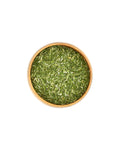 Bowl of green dried herbs on a white background