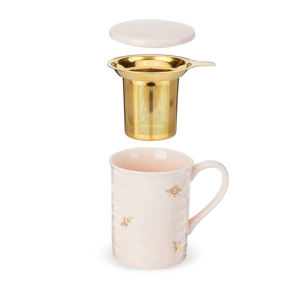 Gold tea infuser over a ceramic mug with bee designs on a white background