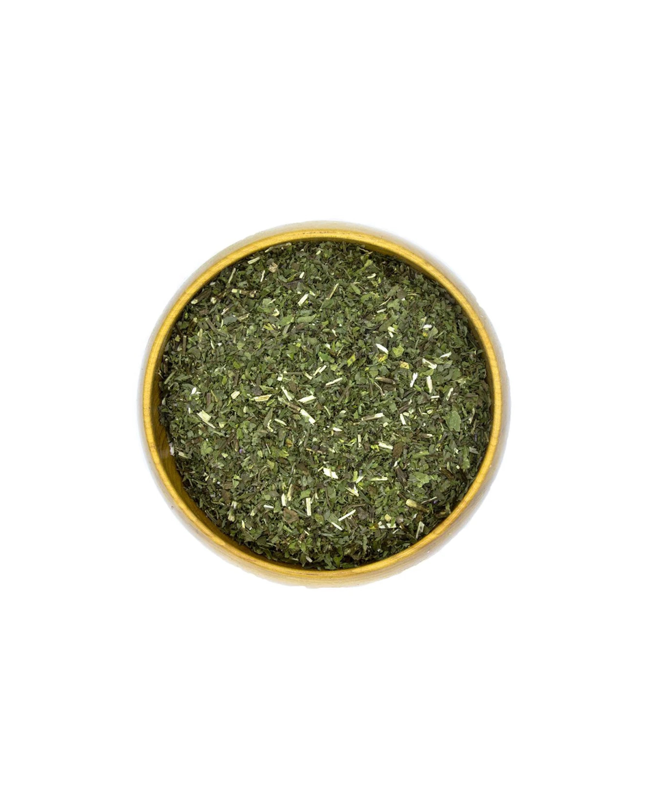 Bowl of dried green herbs on a white background