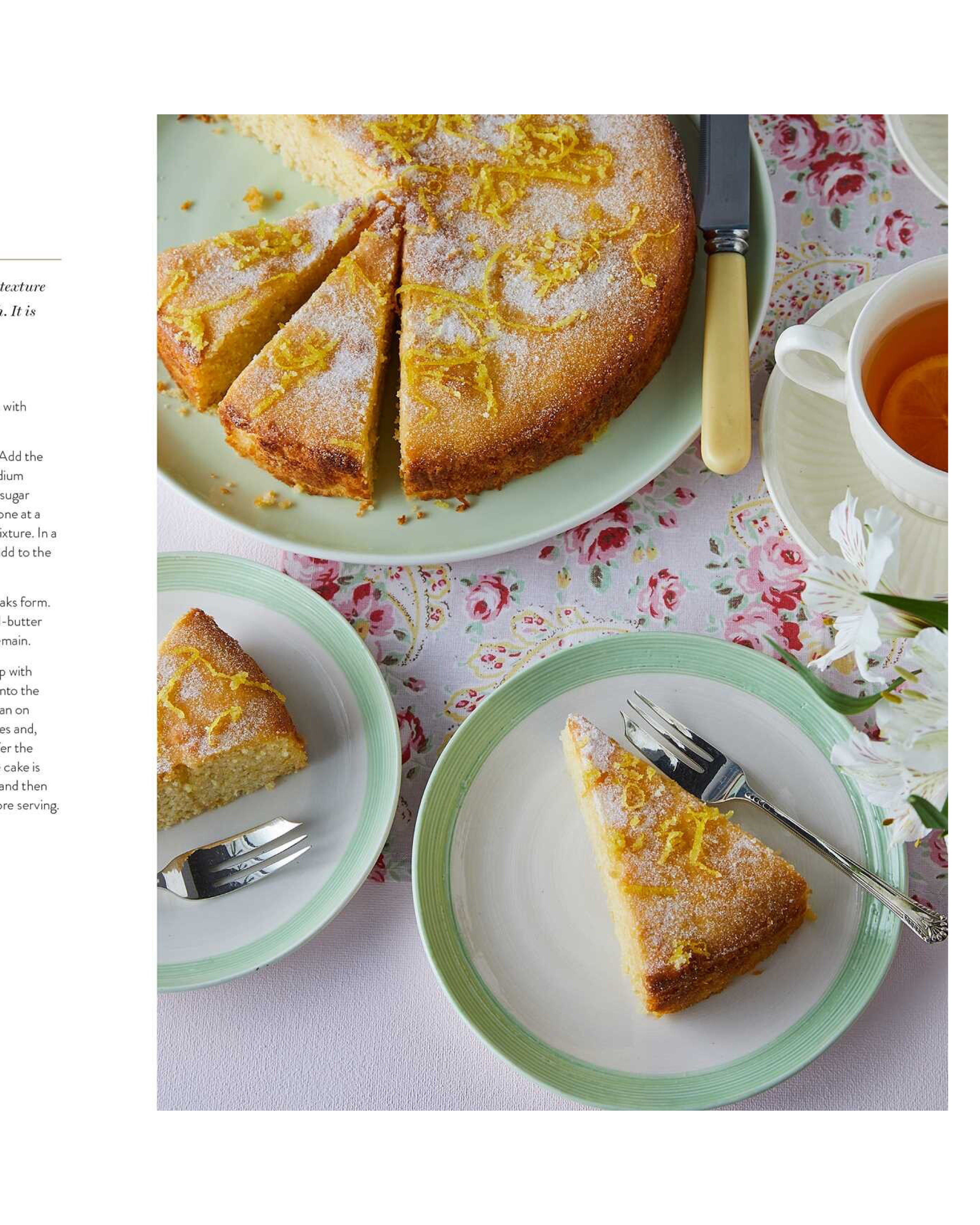 Sliced cake on a plate with a cup of tea and flowers on a floral tablecloth